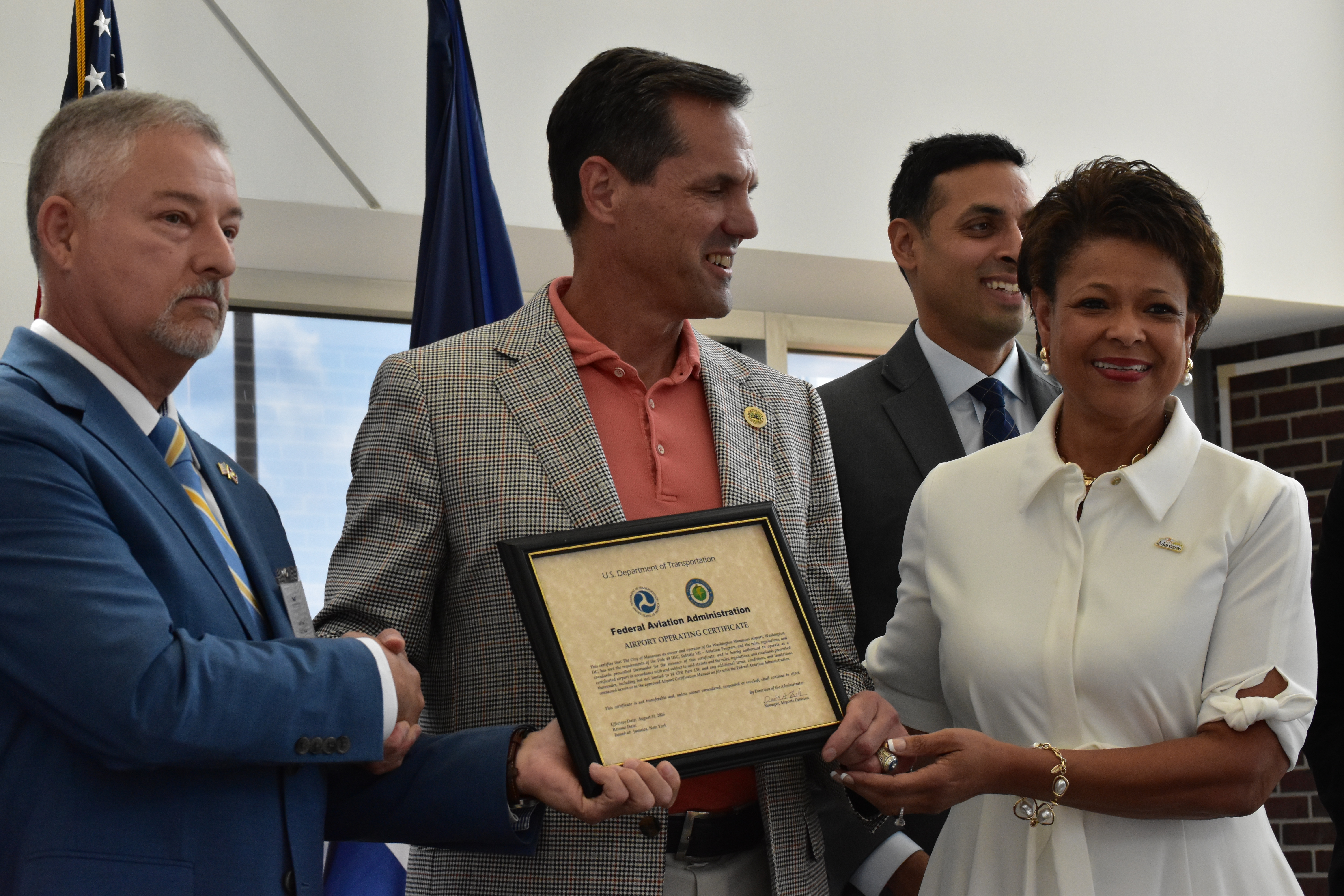Airport Director Juan Riveram FAA Associate Administrator and Mayor of the CIty of Manassas hold the signed Aiprort Operating Certificat on stage.
